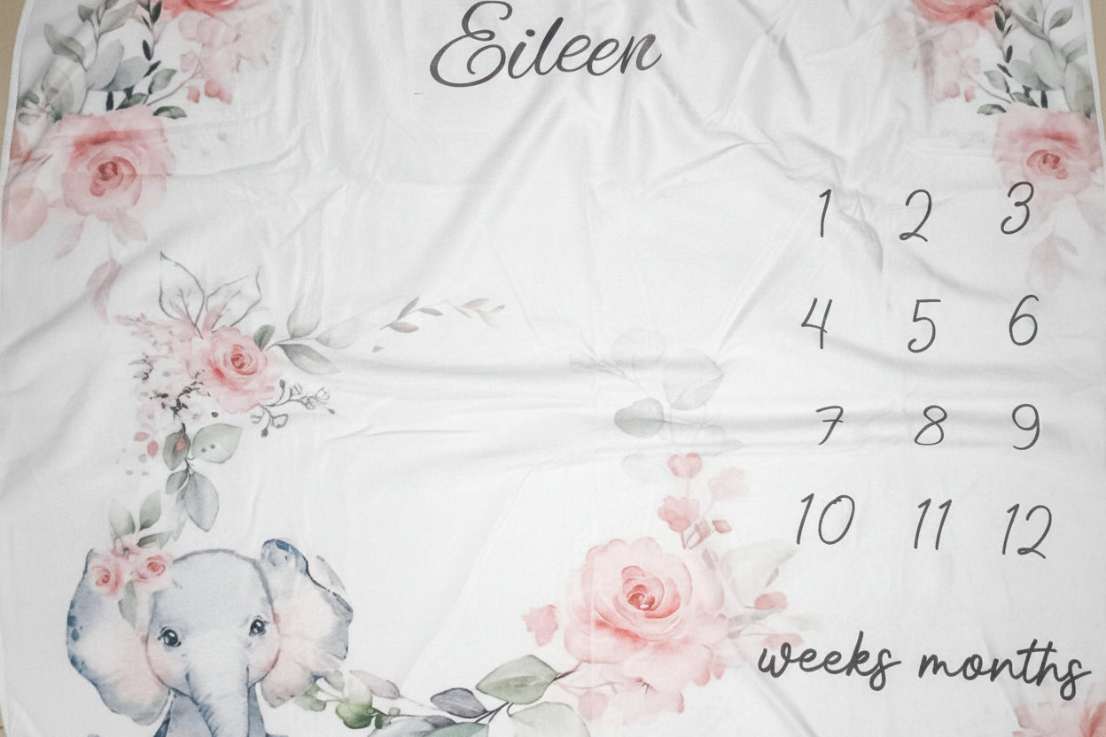Baby milestone blanket with floral designs, elephant illustration, and numerical sequence.